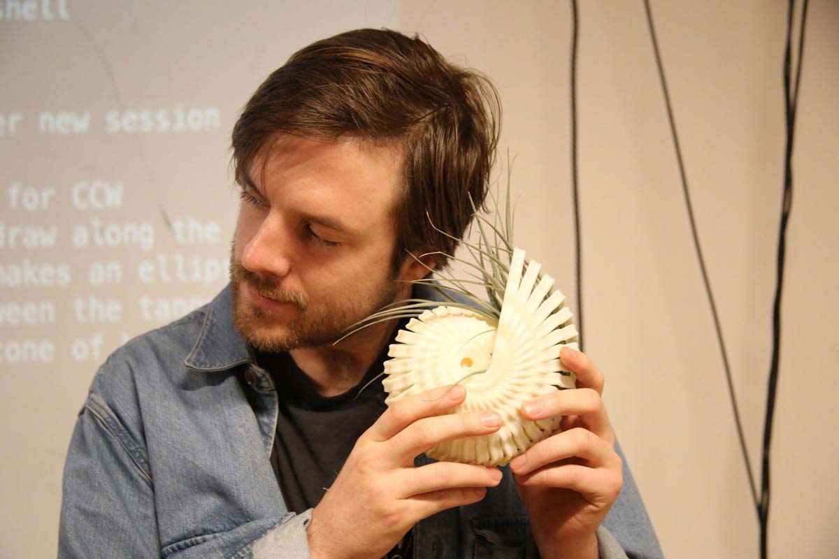 a man holding a spiral shell with leaves coming out